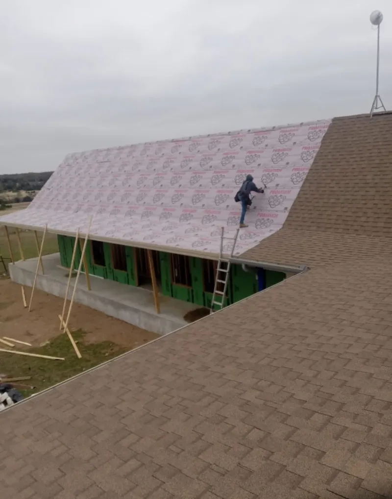 Worker preparing underlayment for a metal roof installation in Owatonna